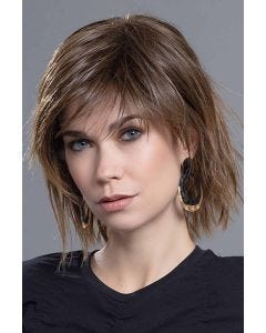 Woman in a shoulder length medium brown wig with spiky textured layers and side bangs