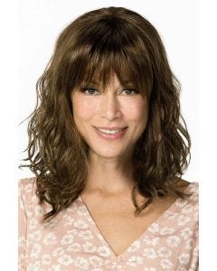 Woman in a past the shoulders wavy medium brown wig with fringe bangs