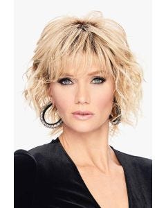 Woman in a chin length layered light blonde curly wig with fringe bangs