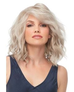 Woman in a past the shoulders light ash blonde wig with defined curls and dark roots