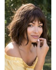 Woman in a shoulder length dark brown wavy wig with fringe bangs