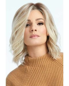 Woman in a shoulder length light blonde curly lace front wig with dark roots