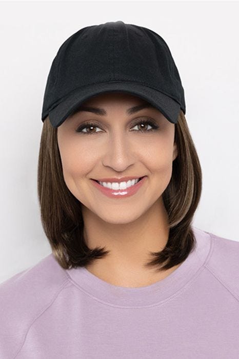 Woman in a solid black baseball cap with shoulder length golden brown hair attached