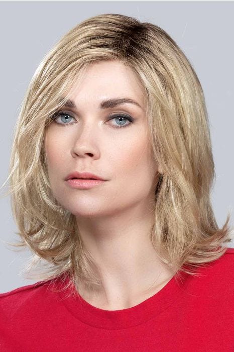 Woman in a shoulder length ash blonde wig with long layers