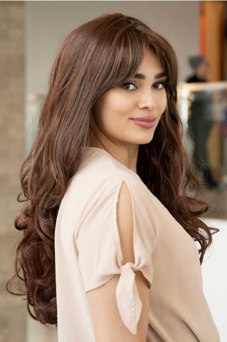 Woman in an extra long light brown curly wig with side bangs