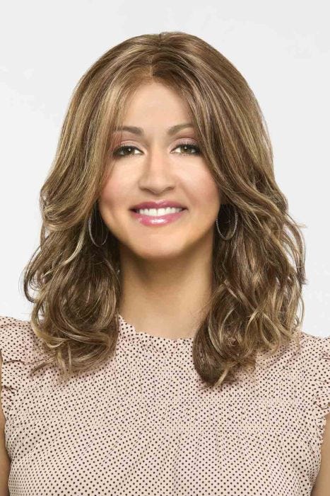 Woman in a past the shoulders light auburn curly wig with long layers