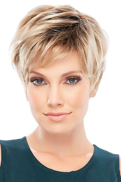Woman in a tousled light blonde pixie wig with dark roots and long layers