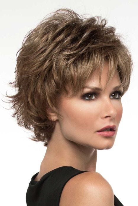 Woman in a petite wavy textured light brown pixie wig with longer piecey layers on top