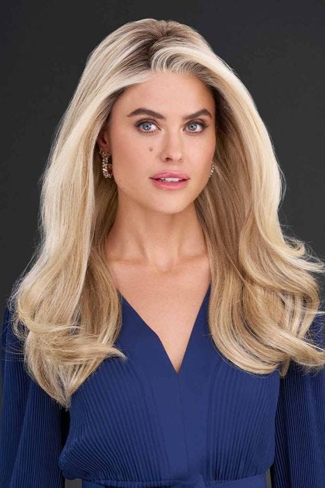 Woman in long, wavy strawberry blonde wig with with long side-swept bangs framing the face