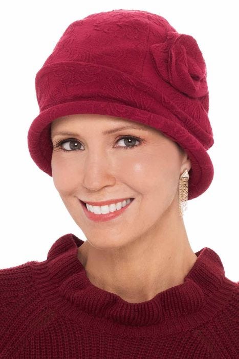 Women in red cloche hat for cancer patients with rose flower on the side