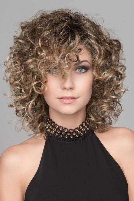 Woman in a full layered, curly light brown shoulder length wig