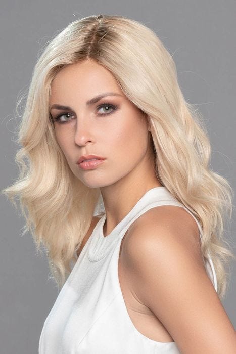Woman in an extra long wavy platinum blonde lace front wig with dark roots