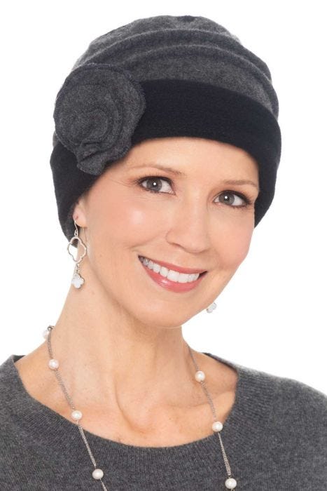 Woman in 2 tone grey winter wool beanie hat with accordion pleats throughout crown and embroidered side flower