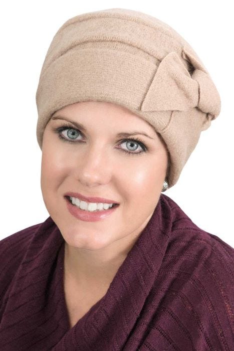 Woman in beige wool beanie style cancer hat with side knot