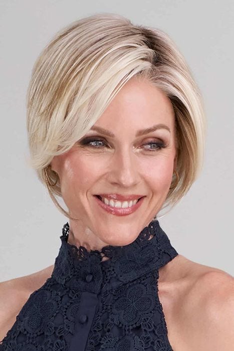Woman in a light blonde angled chin length bob wig with dark roots