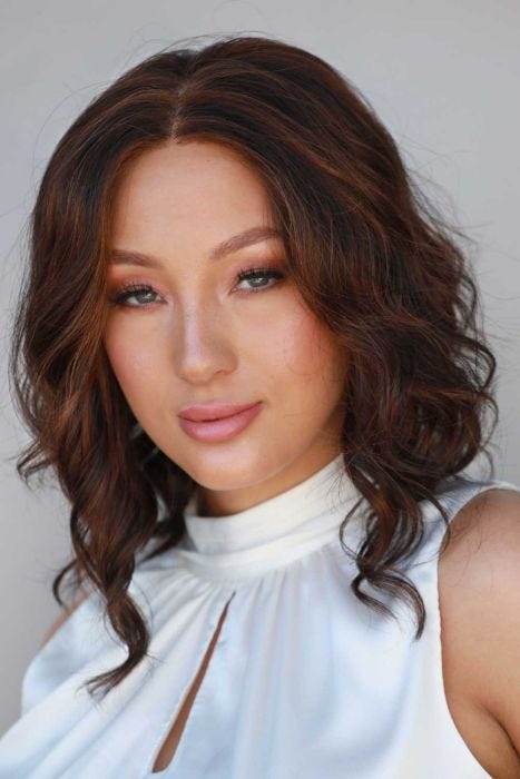 Woman in a petite past the shoulders dark auburn curly lace front wig