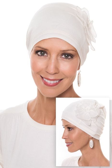 Women in cream beanie style sleep cap with pretty side flower decoration for chemo patients
