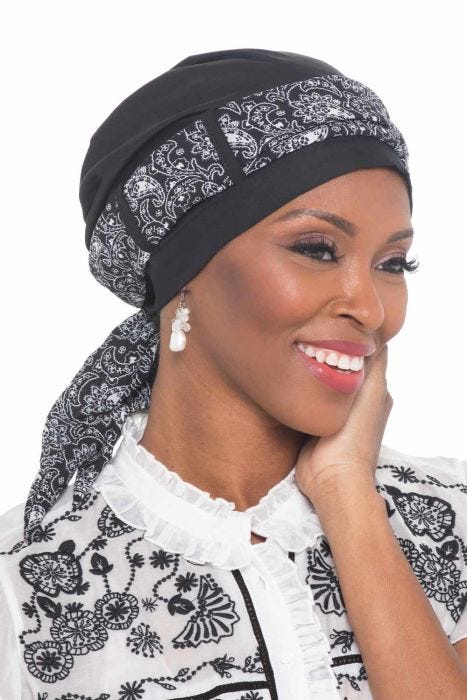 Woman in taupe turban with scarf looped through the head covering