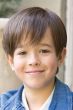 Young boy in a short, layered children's wig with longer layers in back and side swept bangs