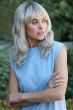 Woman in a past the shoulders wavy medium brown wig with fringe bangs