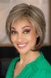 Woman in a shoulder length short light brown wig with long layers and side bangs