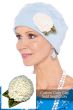 Woman in a light blue cozy cap with a white crocheted dahlia flower pin attached
