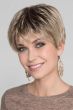 Woman in a classic light blonde pixie wig with dark roots and choppy bangs