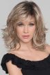 Woman in a shoulder length wavy layered light blonde wig with side bangs