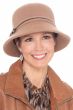 Woman in structured beige wool felt winter hat with brim in a bucket or cloche style with petite bow on the side
