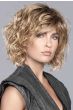 Woman in a past chin length gold blonde curly wig with side bangs
