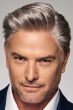 Man in a cropped light grey brushed back human hair wig with shorter sides