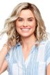 Woman in a past the shoulders light ash blonde wig with defined curls and dark roots