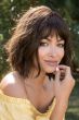 Woman in a shoulder length dark brown wavy wig with fringe bangs
