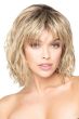 Woman in a shoulder length light blonde curly lace front wig with fringe bangs
