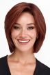 Woman in a chin length warm blonde wig with choppy layers and side bangs