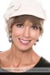 Woman in a short wavy ash blonde halo wig under a cream newsboy hat