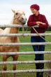 Woman outdoors with horse wearing red slouchy beanie chemo hat