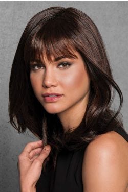 Woman in a past the shoulders layered dark auburn wig with arched bangs