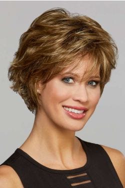 Woman in a long golden brown pixie wig with layers and wispy bangs