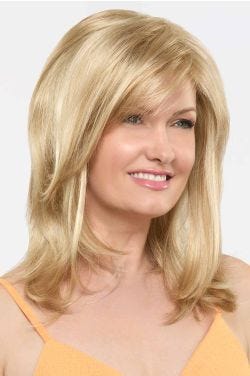 Woman in a past the shoulders warm blonde wig with wispy side bangs