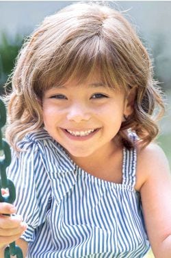 Little girl in a shoulder length light brown curly children's lace front wig