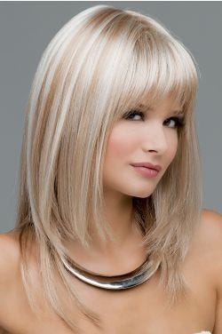 Woman in a long, past the shoulders platinum blonde wig with shoulder length layered and feathered bangs