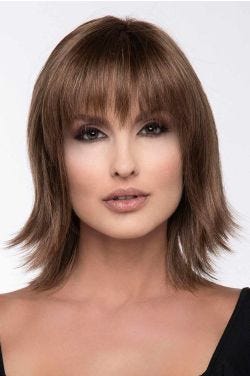 Woman in a shoulder length light brown wig with long feathered layers and fringe bangs