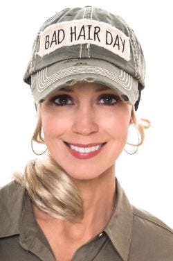 Woman in olive baseball cap with "Bad Hair Day" embroidered patch on the front