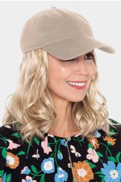 Woman in black baseball cap with blonde curly long hair attached