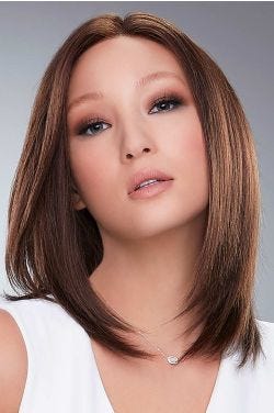 Woman in a past the shoulders medium auburn human hair wig with long layers