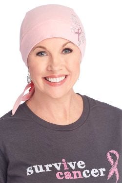 Older woman in pink do rag style head wrap with breast cancer ribbon