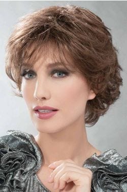 Woman in a short layered medium auburn curly wig with bangs