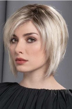 Woman in a past the chin platinum blonde stacked bob wig with choppy layers and side bangs