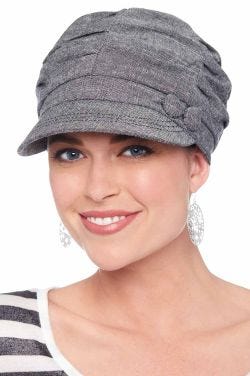 Woman in grey colored paperboy hat with pleats on top and side button for cancer patients